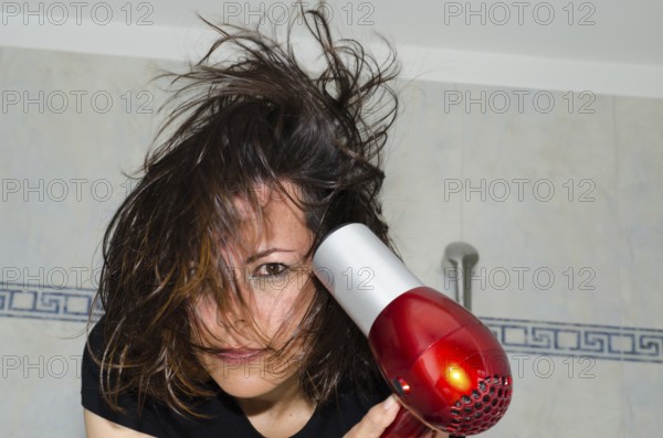 Portrait of a Beautiful Woman Drying Her Hair with a Hair Dryer in Bathroom in Switzerland