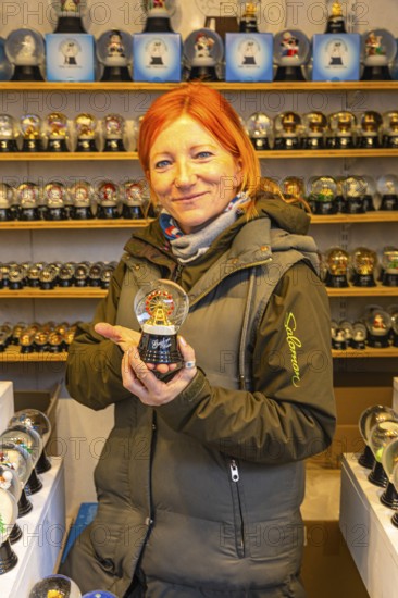 Saleswoman presenting a snow globe in a stand for snow globes at the Christmas market at St Stephen's Cathedral, Stephans-Platz, Vienna, Austria, Europe