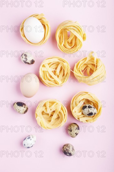 Raw uncooked tagliatelle pasta with quail eggs on a pink pastel background. top view, copy space