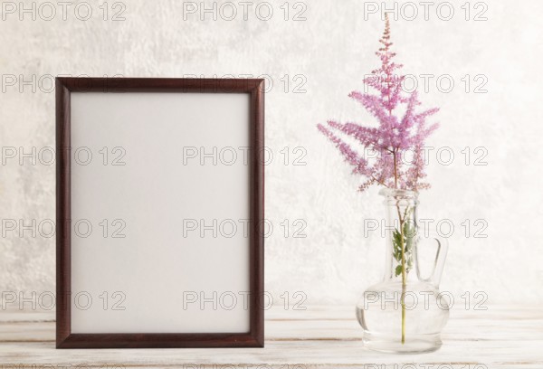 Wooden frame with pink astilbe flowers in glass vase on gray concrete background. side view, copy space, still life, mockup, template, spring, summer concept