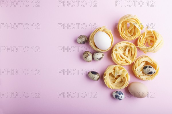 Raw uncooked tagliatelle pasta with quail eggs on a pink pastel background. top view, copy space