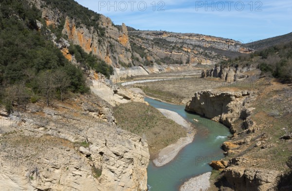 A river meanders through a deep gorge in the middle of a rocky landscape under a blue sky, Noguera Ribagorçana Mont-rebei Natural Park, Montsec mountain range, Noguera Ribagorçana river, Lleida province, Catalonia, Aragon, Spain, Europe