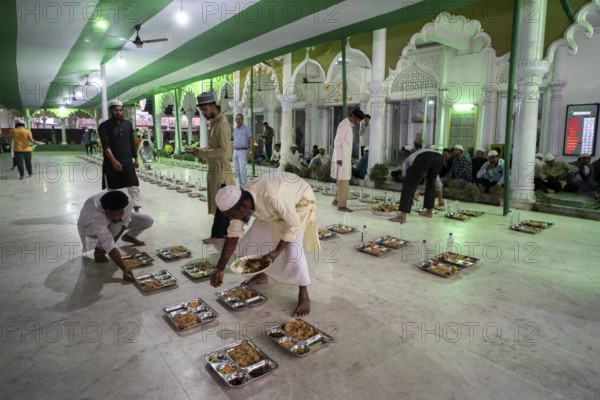 Volunteers distribute and arrange rows of 'iftar' meal for devotees to break their fast, during the holy month of Ramadan, at Burha Jame Masjid, on March 13, 2024 in Guwahati, Assam, India, Asia