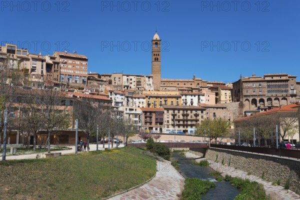 Historic town with a central stone tower, river in the foreground and several residential buildings under a blue sky, church, Iglesia de Santa María Magdalena, episcopal palace, Palacio Episcopal, Rio Queiles, Tarazona, Zaragoza, Aragon, Spain, Europe