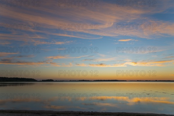 Peaceful sunrise over a smooth lake with pastel-coloured sky and reflections, sunset, Zatoka Wrzosowska, Lake Fritzow, Dziwnow, Zachodniopomorskie, West Pomerania, Poland, Europe