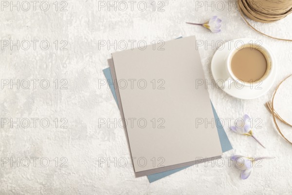 Gray paper sheet mockup with spring snowdrop crocus flowers and cup of coffee on gray concrete background. Blank, business card, top view, flat lay, copy space, still life. spring concept