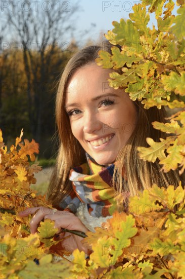 Portrait of young beautiful smiling woman, 30 years old, outdoors in forest with autumn colors in Ystad, Skåne County, Sweden, Scandinavia, Europe