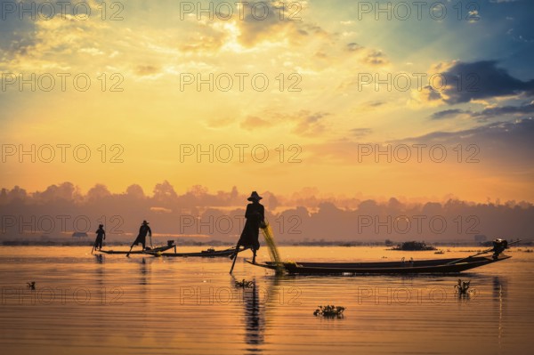 Myanmar travel attraction landmark, traditional Burmese fishermen sihouettes at Inle lake on sunset, Myanmar famous for their distinctive one legged rowing style