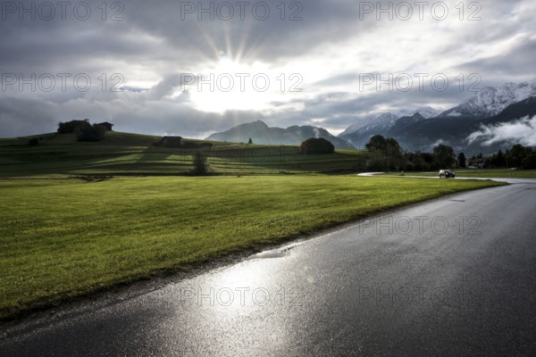 After a rain shower, the sun appears for a moment in the otherwise cloudy sky in front of the mountain backdrop in Pfronten, 13 October 2021