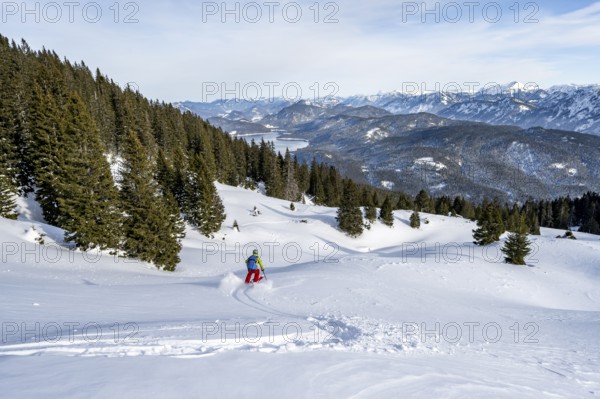 Skiers skiing down the Simetsberg, view of Walchensee and mountain panorama, Estergebirge, Bavarian Prealps, Bavaria Germany