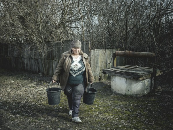 Larisa draws water from a well in Borshchivka. The village was under Russian occupation. She hid with her granddaughter Angelina in her house for almost six months, Borshchivka, Raion Isyum, Kharkiv Oblast, Ukraine, Europe