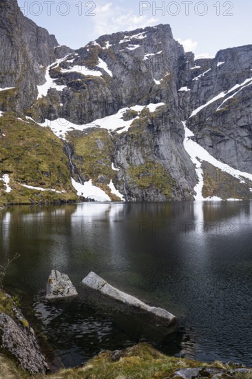 Lake Reinevatnet is located on the Reinebringen mountain. Rock faces with remnants of snow in early summer. Evening, good weather. Reine, Moskenesoya, Lofoten, Norway, Europe