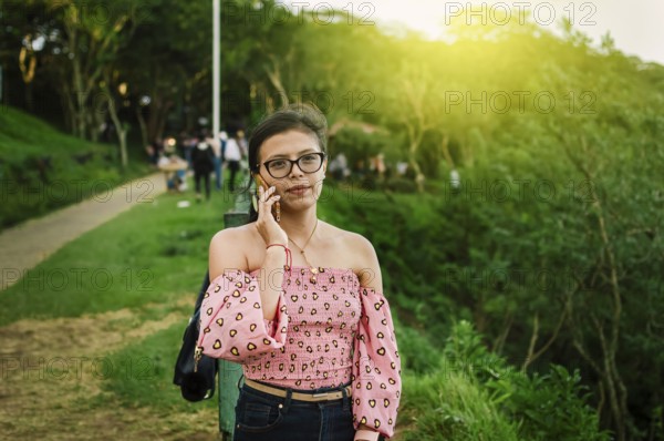 Portrait of latin woman phone in the park. Close up of girl in glasses calling phone outdoor