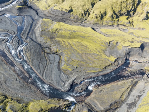 River along road F232 Öldufellsleid, slopes of Mt. Öldufell, moss-covered hill in black lava sand, aerial view, Iceland, Europe