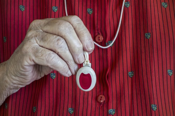 Close up of hand holding life-saving personal alarm for the elderly and disabled people showing pendant with push button