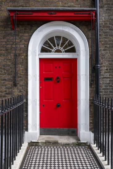 Red entrance door in a brick building with a cast-iron fence, Charles Dickens Museum, 48-49 Doughty Street, Holborn, London Borough of Camden, England, United Kingdom, Europe