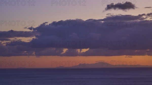 Sunrise over the sea with orange-violet sky and dense clouds, Rhodes on the horizon, morning light, sunrise, coastal road, east coast, Karpathos, Dodecanese, Greek Islands, Greece, Europe