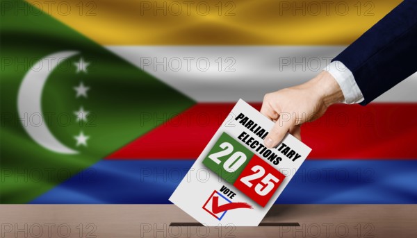 Hand holding ballot in voting ballot box with Comoran flag in background. Comoran parliamentary elections