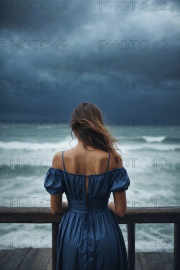 A depressed lonely woman is standing on an ocean shore wearing a blue dress, AI generated