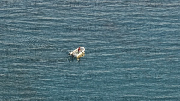 Single boat with one person on calm blue sea in the distance, Anthony Quinn Bay, Vagies Bay, Rhodes, Dodecanese, Greek Islands, Greece, Europe