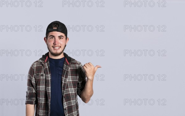 Cheerful bearded man with a friendly smile shows you the direction to a nice place, a friendly guy pointing his thumb to his right