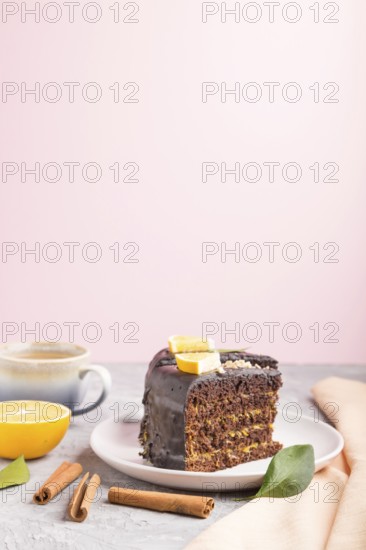 Homemade chocolate cake with orange and cinnamon with cup of coffee on a gray and pink background with orange textile. side view, selective focus, copy space