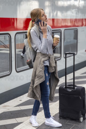 Young woman standing on the railway track in front of a train