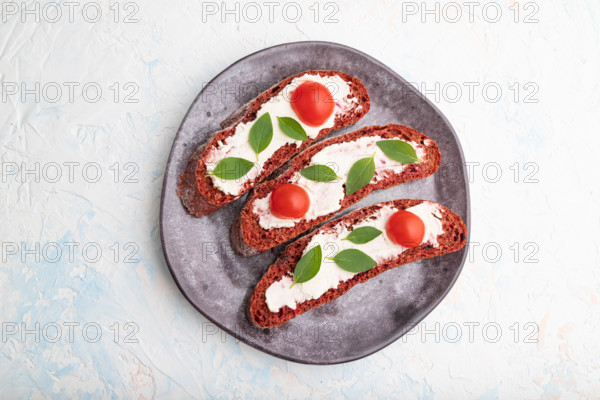 Red beet bread sandwiches with cream cheese and tomatoes on white concrete background. top view, flat lay, close up