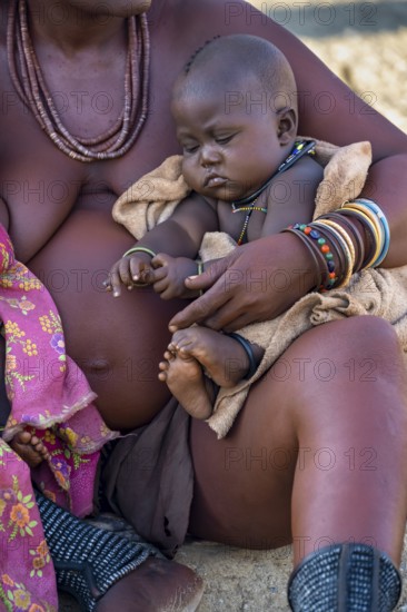 Baby in the arms of a Himba woman, traditional Himba village, Kaokoveld, Kunene, Namibia, Africa