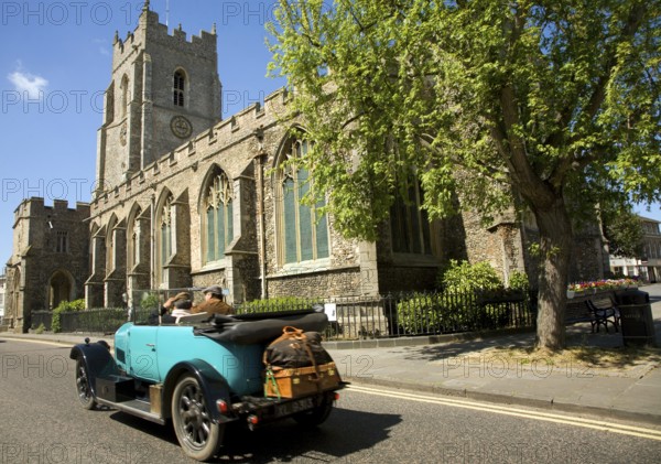 Classic veteran car passing Church of Saint Peter, Sudbury, Suffolk, England, United Kingdom, Europe