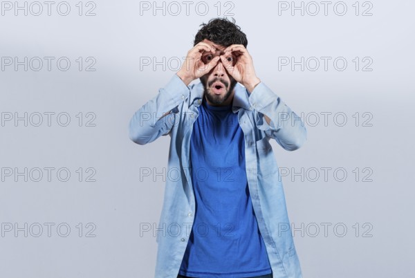 Curious man making binoculars gesture isolated. Guy making binoculars gesture isolated. Man making binoculars gesture