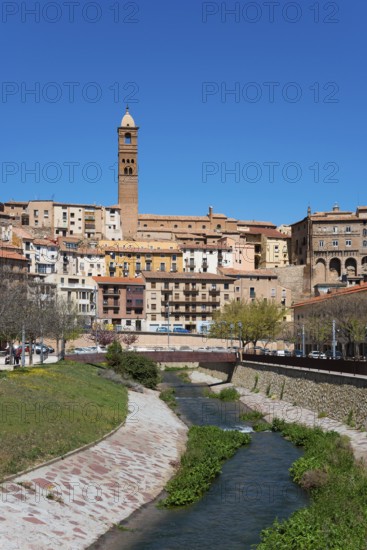 Historic town with a stone tower, river in the foreground and several shops and residential buildings under a blue sky, church, Iglesia de Santa María Magdalena, Rio Queiles, Tarazona, Zaragoza, Aragon, Spain, Europe