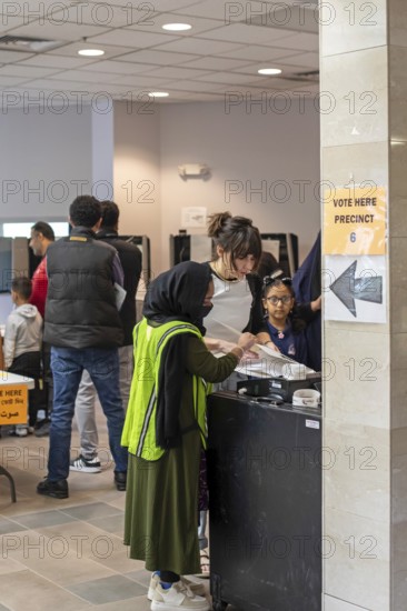 Hamtramck, Michigan USA, 5 November 2024, Voters cast ballots in the 2024 presidential election in Hamtramck, where the Muslim mayor, Amer Ghalib, has endorsed Donald Trump. An election worker helps a voter run her ballot through the counting machine