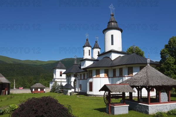 A peaceful Orthodox church with white walls and black roofs in front of a mountain, Cheia Romanian Orthodox Monastery, Maneciu, Maneciu, Prahova, Wallachia, Romania, Europe