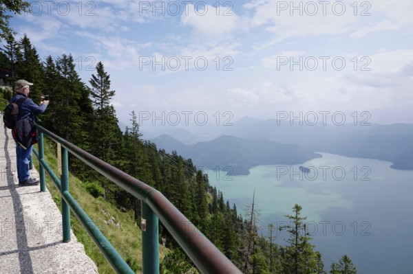 Hiker with mobile phone with view to Walchensee, August, Bavaria, Germany, Europe