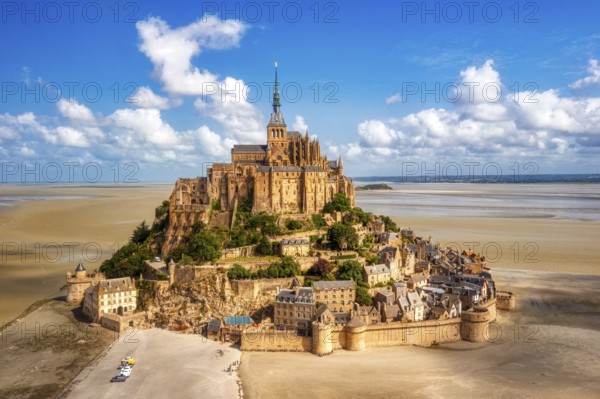 Island abbey majestically enthroned above sandy ground and under a clear sky, Le Mont-Saint-Michel