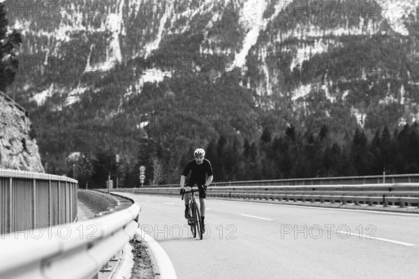 Road bike rider in spring between Lechtal and Tannheimer Tal in front of picturesque scenery of the Alps, Tyrol, Austria, Europe