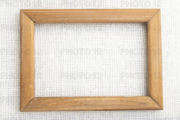 Wooden frame on smooth white linen tissue. Top view, flat lay, natural textile background and texture