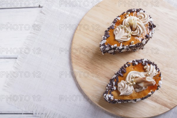 Cakes with chocolate chips and cream decorations on wooden board on white background. selective focus, close up, copy space