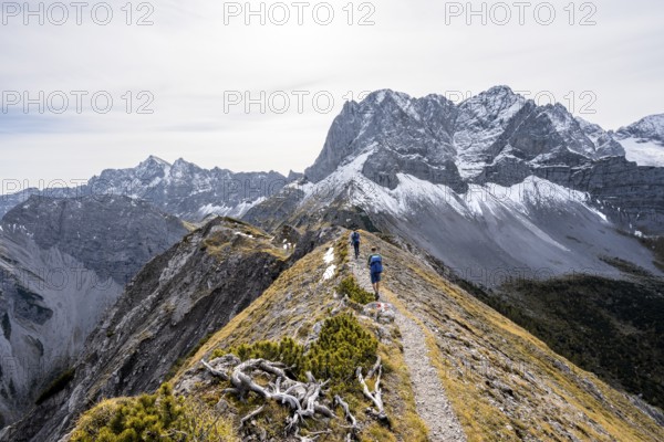 Two mountaineers on a hiking trail on the ridge of Hahnkampl, mountain panorama with rocky steep peaks, view of summit Lamsenspitze, Karwendel Mountains, Alpenpark Karwendel, Tyrol, Austria, Europe