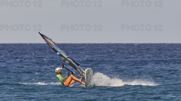 Person in green t-shirt balancing on a wave with a windsurfing board, windsurfer, Meltemi windsurfing spot, Devils Bay, Paralia Vatha, Vatha Beach, Southeast coast, Karpathos, Dodecanese, Greek Islands, Greece, Europe