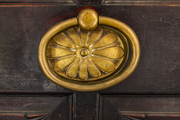 Historic brass door knob on a wooden door, background