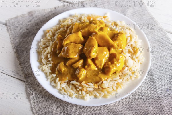 Rice with chicken curry sauce with cashew on white wooden background. top view, close up