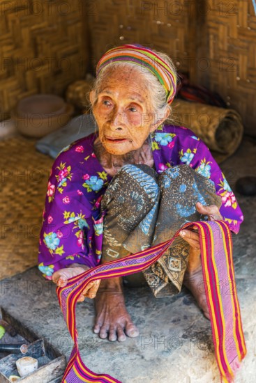 Old woman offering textiles for sale, textile, old age, human, work, colourful, clothing, village, offer, sell, woman, trade, bazaar, authentic, fabric, fabric pattern, craft, handicraft, Asian, indigenous, tradition, traditional, marketplace, travel, tourism, culture, poverty, presentation, lifestyle, person, Muslim, Islam, Sasak, indigenous, indigenous people, cultural heritage, silk weaving, portrait, human, village Sade, Lombok, Indonesia, Asia