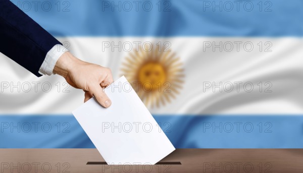 Hand holding ballot in voting ballot box with Argentina flag in background. Hand man puts ballot paper in voting box on Argentina flag background. Argentina electoral elections, concept