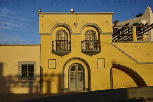 Yellow building with decorative balconies and large windows, illuminated by the last evening light, town hall, Dimarchio, Pigadia, town and harbour, Pigadia Bay, main town, Karpathos, Dodecanese, Greek Islands, Greece, Europe