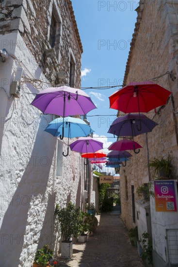 Narrow alley decorated with a row of colourful floating umbrellas, Old Town, Areopoli, Areopolis, Tsimova, Itylo, Anatoliki Mani, Mani, Laconia, Peloponnese, Greece, Europe