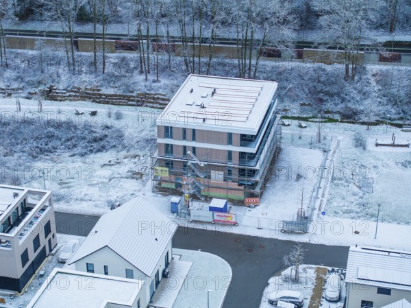 A snow-covered building under construction with trees and road in an urban landscape, Nagold, Black Forest, Germany, Europe