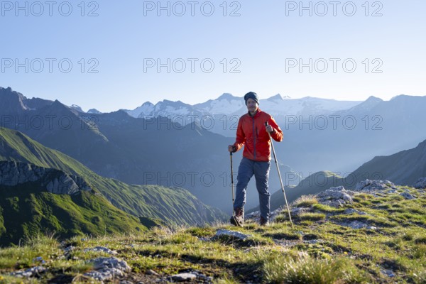 Hiker enjoying the mountain panorama in the morning, Venediger group, behind Dreiherrenkopf, Simonysitze and Großer Geiger, Hohen Tauern, Austria, Europe