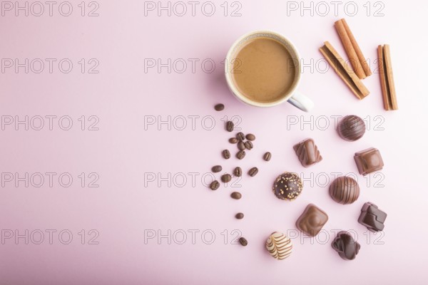 Different chocolate candies and a cup of coffee on a pink pastel background. top view, flat lay, copy space